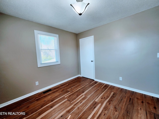 unfurnished room with hardwood / wood-style floors and a textured ceiling