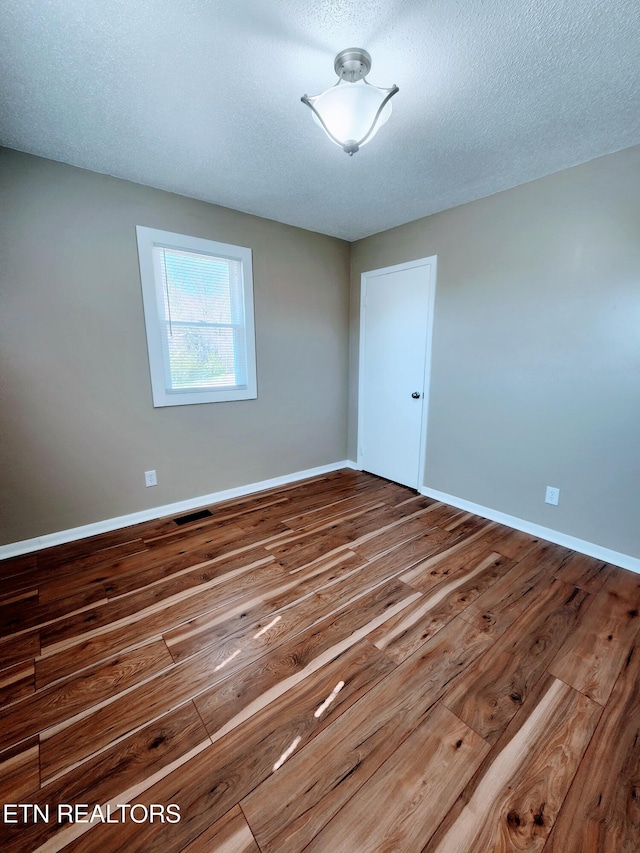 spare room with wood-type flooring and a textured ceiling