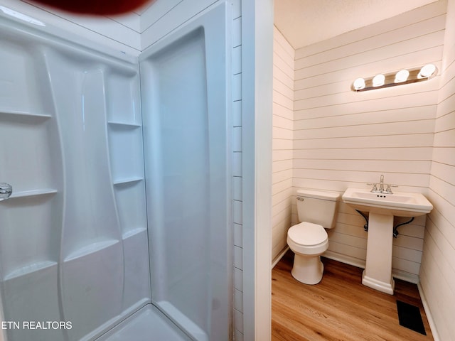 bathroom with walk in shower, toilet, wood walls, and hardwood / wood-style floors