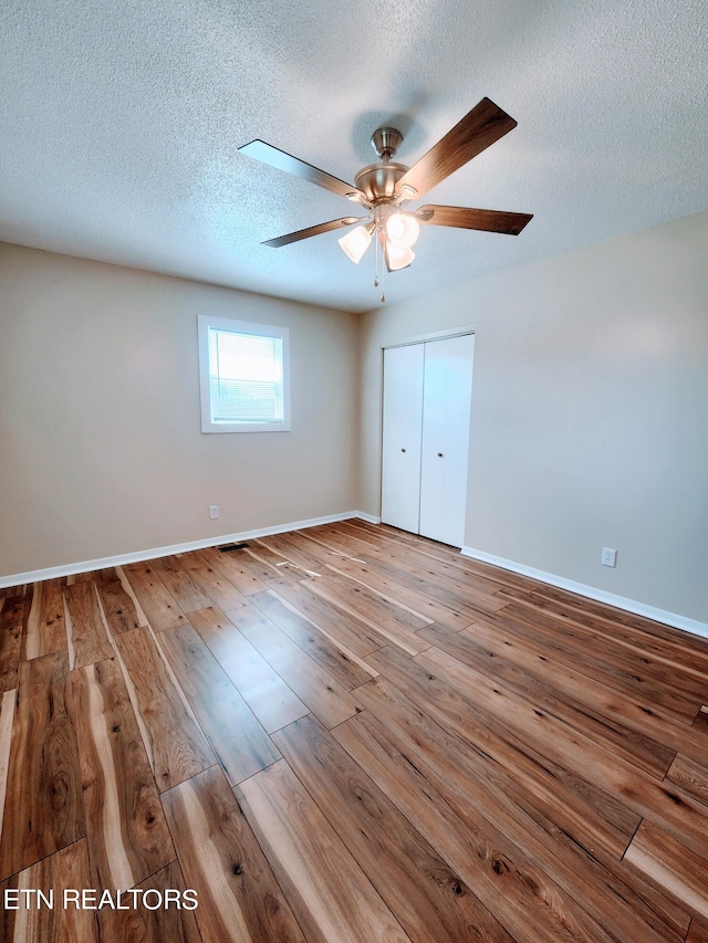 unfurnished bedroom featuring a closet, hardwood / wood-style floors, a textured ceiling, and ceiling fan