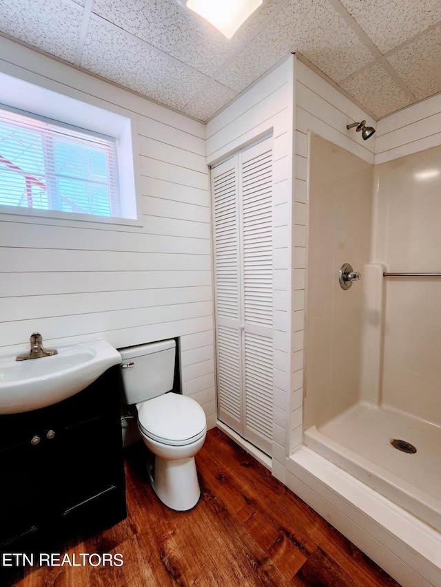 bathroom with walk in shower, vanity, hardwood / wood-style floors, and toilet