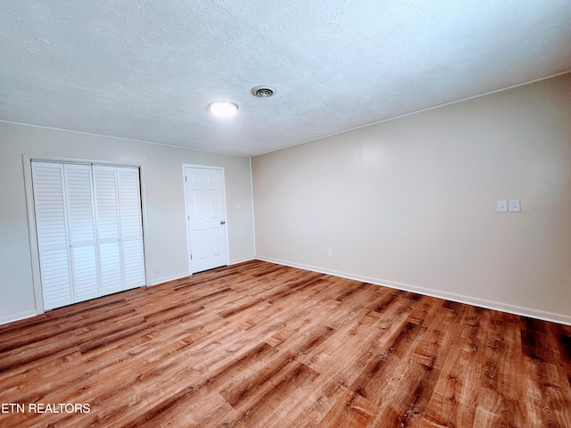 unfurnished bedroom with hardwood / wood-style flooring and a textured ceiling