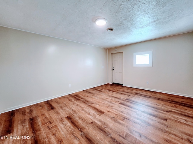 unfurnished room with a textured ceiling and light hardwood / wood-style flooring