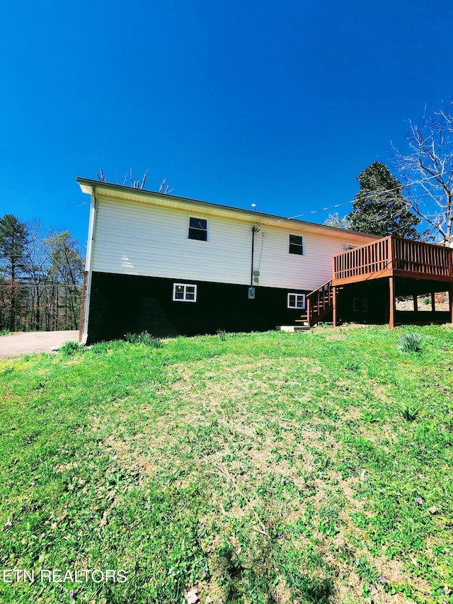 back of house featuring a wooden deck and a lawn