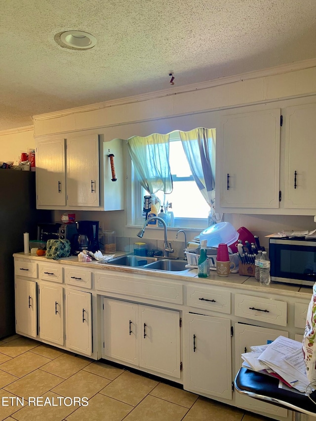 kitchen with white cabinets, light tile patterned flooring, sink, and ornamental molding