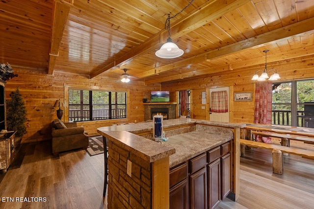 kitchen with beamed ceiling, wooden walls, plenty of natural light, and light hardwood / wood-style floors