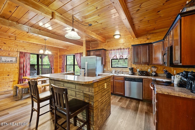 kitchen with stainless steel appliances, plenty of natural light, wood walls, and a kitchen island