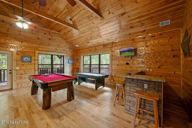 rec room featuring a healthy amount of sunlight, beam ceiling, wood walls, and light hardwood / wood-style flooring