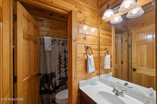 bathroom with a shower with curtain, vanity, wooden walls, and toilet