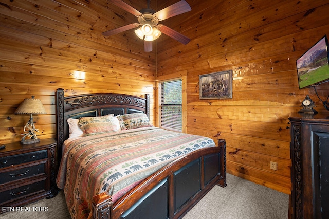 carpeted bedroom with ceiling fan and wood walls