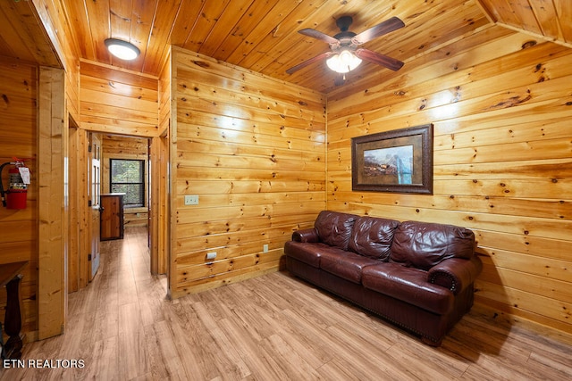 living room with lofted ceiling, light wood-type flooring, wood walls, and wooden ceiling