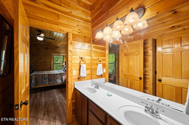 bathroom featuring wood-type flooring, wooden walls, vanity, and ceiling fan