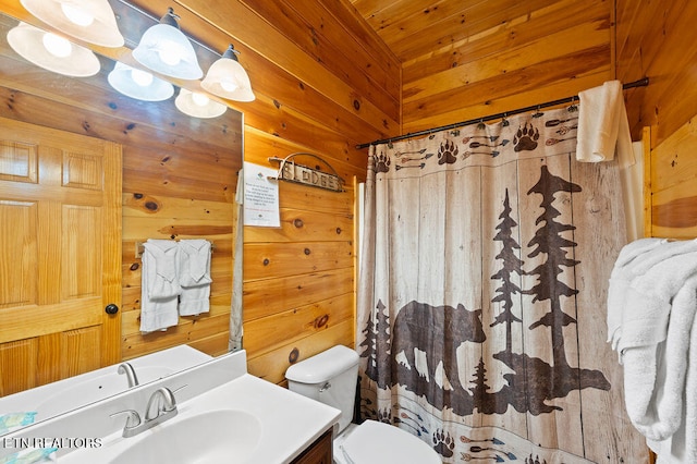 bathroom with wooden walls, a shower with shower curtain, vanity, and toilet