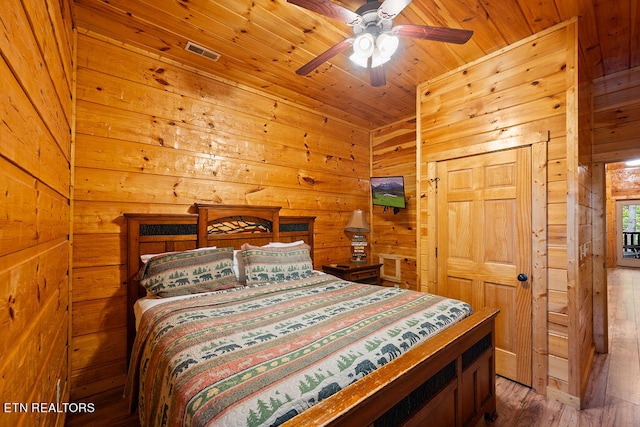 bedroom with ceiling fan, wooden walls, hardwood / wood-style floors, and wood ceiling