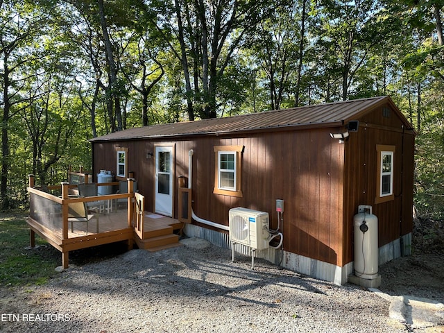 back of property featuring ac unit, an outbuilding, and a deck