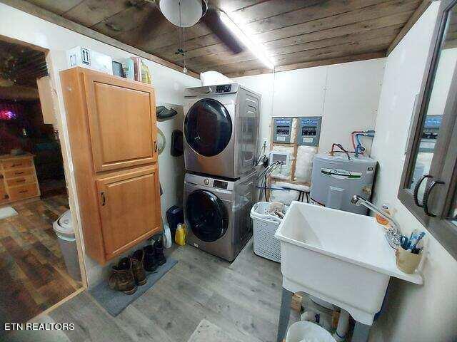 washroom with water heater, wood ceiling, stacked washing maching and dryer, and light hardwood / wood-style floors