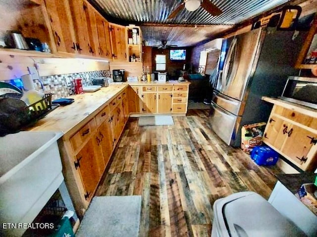 kitchen with appliances with stainless steel finishes, kitchen peninsula, ceiling fan, and dark hardwood / wood-style flooring