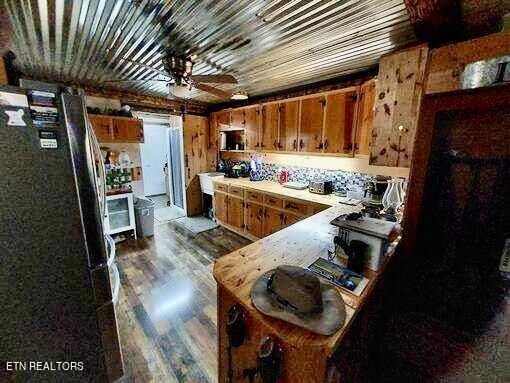 kitchen featuring ceiling fan, black fridge, light hardwood / wood-style floors, and kitchen peninsula