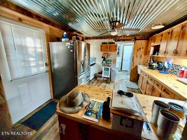 kitchen featuring stainless steel refrigerator with ice dispenser, wooden walls, a barn door, and hardwood / wood-style flooring