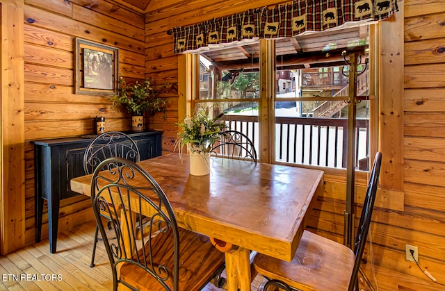 dining space featuring light wood-type flooring and wood walls