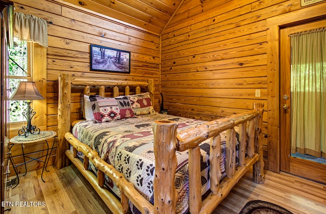 bedroom with hardwood / wood-style floors, wooden walls, vaulted ceiling, and wooden ceiling