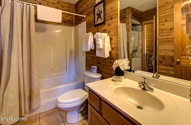 full bathroom with stacked washer and dryer, wooden walls, vanity, and toilet