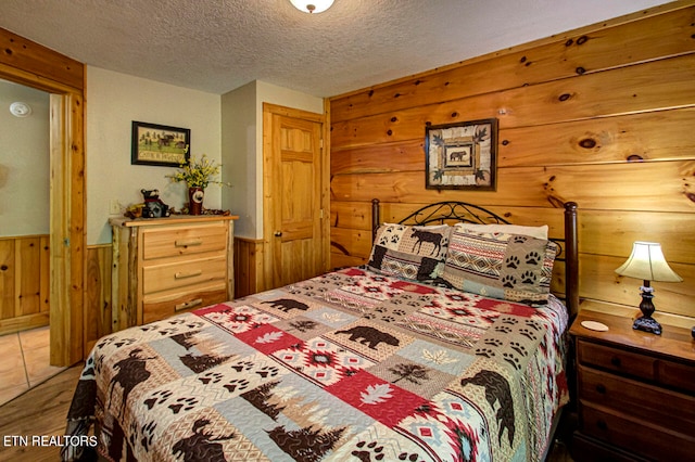 bedroom with a textured ceiling, wood walls, and tile patterned floors