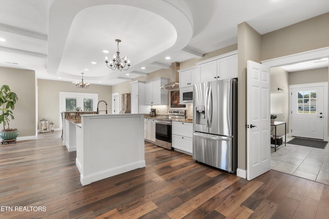 kitchen with appliances with stainless steel finishes, dark wood-type flooring, a kitchen island with sink, and white cabinets