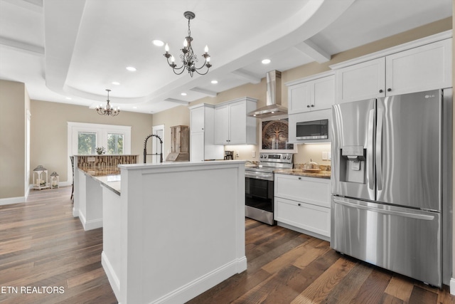 kitchen featuring pendant lighting, white cabinets, a center island with sink, wall chimney range hood, and stainless steel appliances