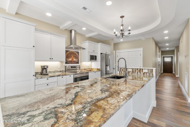 kitchen featuring wall chimney exhaust hood, hardwood / wood-style floors, sink, stainless steel appliances, and white cabinetry