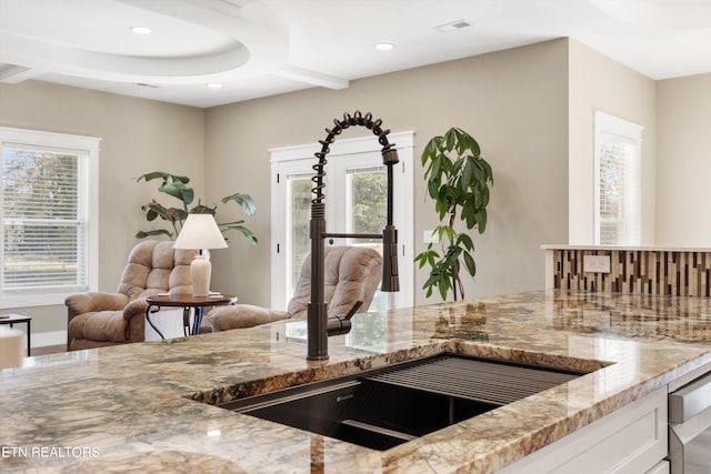 kitchen with sink, dishwashing machine, light stone counters, and white cabinetry