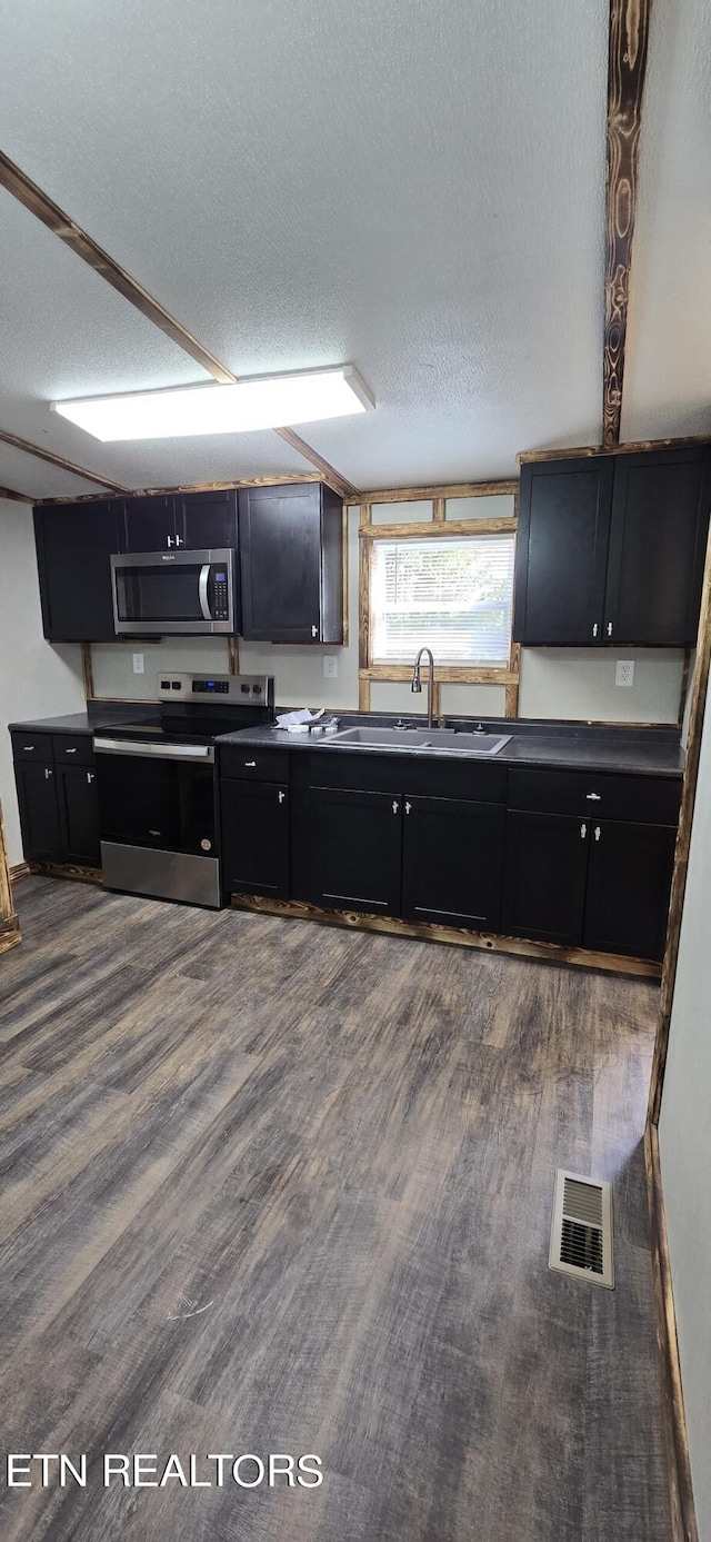 kitchen with sink, stainless steel appliances, a textured ceiling, and hardwood / wood-style flooring