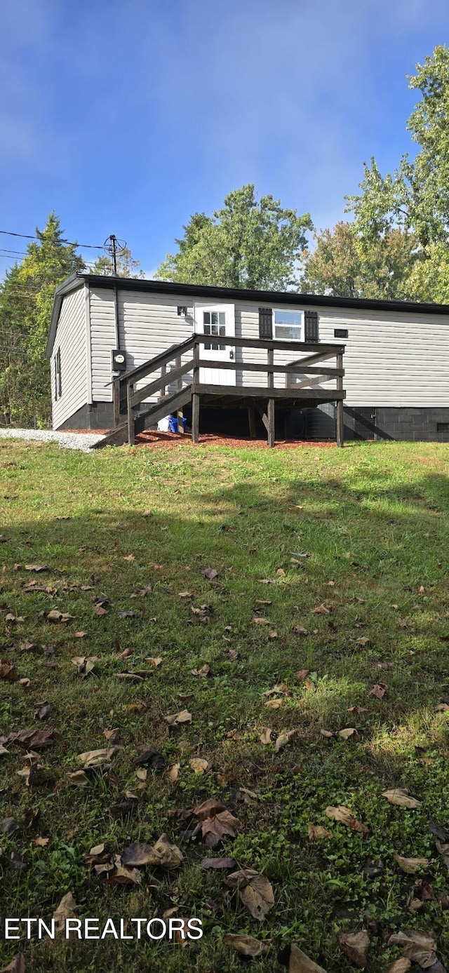 rear view of property with a wooden deck and a lawn