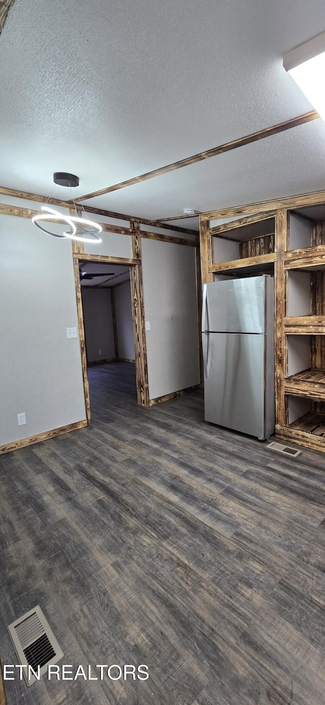 interior space with stainless steel fridge, a textured ceiling, and dark wood-type flooring