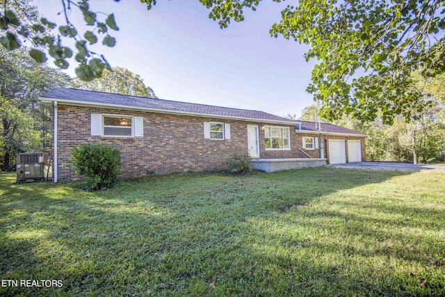 single story home with a garage, a front yard, and central AC