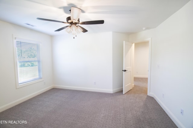 spare room featuring carpet floors, baseboards, ceiling fan, and visible vents