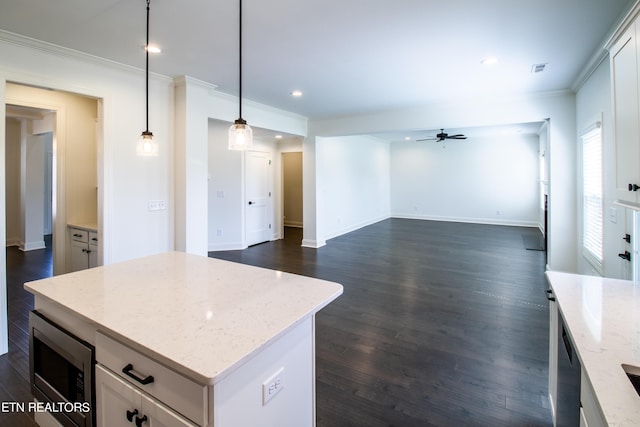 kitchen featuring crown molding, ceiling fan, white cabinetry, stainless steel microwave, and open floor plan
