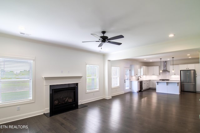 unfurnished living room with a sink, a fireplace with raised hearth, a ceiling fan, recessed lighting, and visible vents