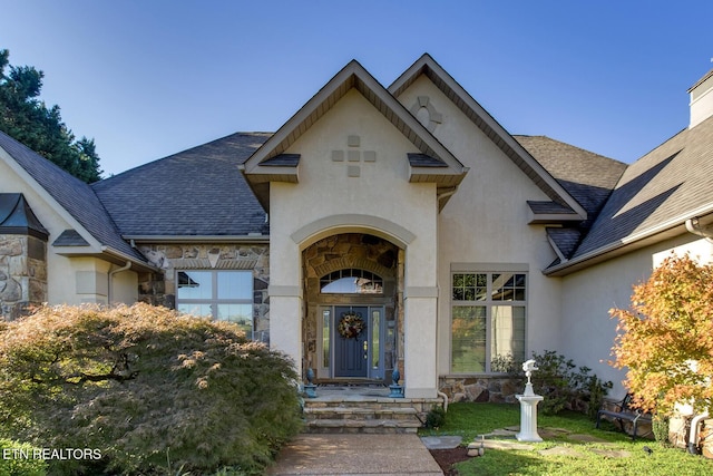 view of front of home featuring a garage, stone siding, roof with shingles, and stucco siding