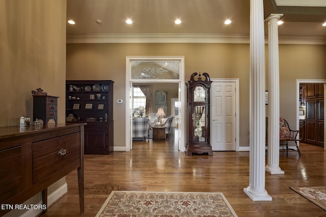 foyer entrance featuring decorative columns, wood finished floors, and ornamental molding