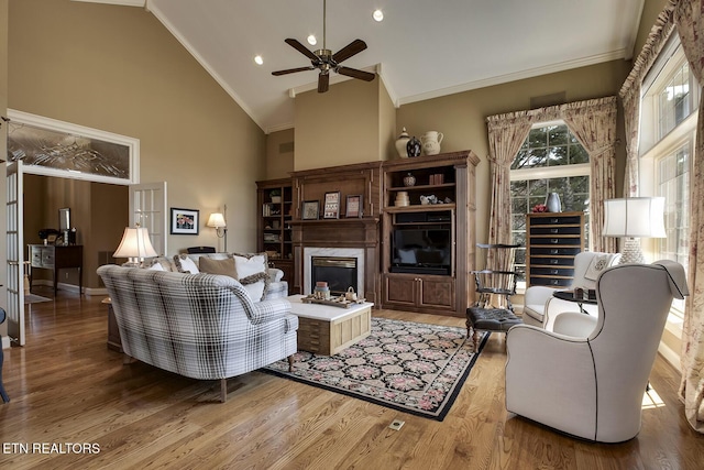 living room featuring high vaulted ceiling, a fireplace, wood finished floors, and crown molding