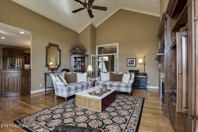 living area with high vaulted ceiling, light wood-type flooring, and baseboards