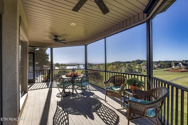 wooden terrace featuring outdoor dining space, ceiling fan, and a water view