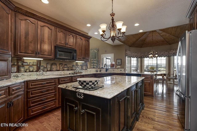 kitchen with a chandelier, a peninsula, black appliances, and wood finished floors