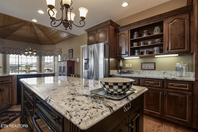 kitchen with light stone countertops, a kitchen island, an inviting chandelier, open shelves, and stainless steel refrigerator with ice dispenser