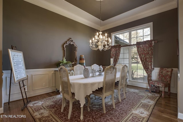 dining space with an inviting chandelier, wood finished floors, wainscoting, and ornamental molding