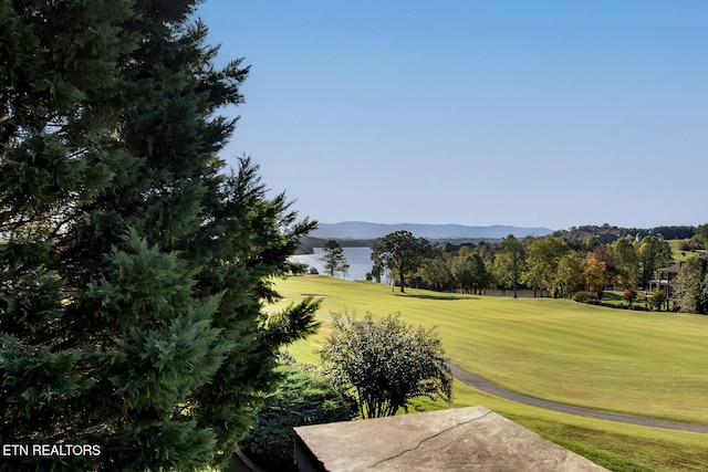 view of property's community with a lawn, a water and mountain view, and view of golf course