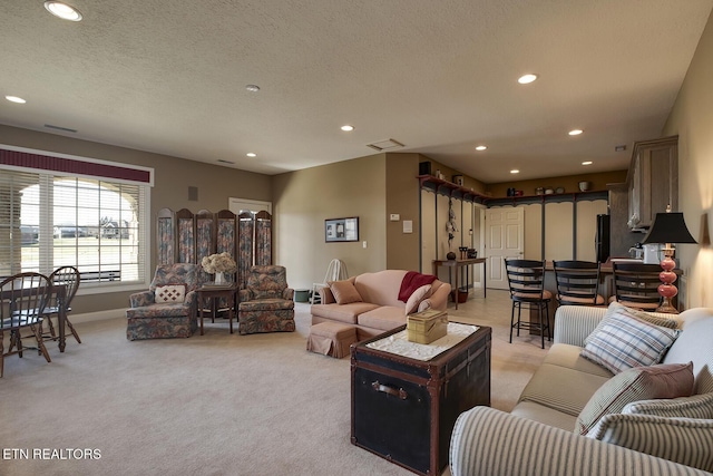 living area with recessed lighting, light colored carpet, and a textured ceiling