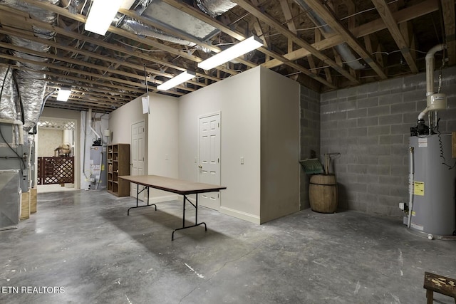 basement with a garage, concrete block wall, and water heater