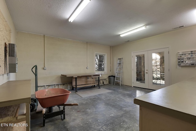 miscellaneous room with french doors, unfinished concrete flooring, a textured ceiling, and visible vents